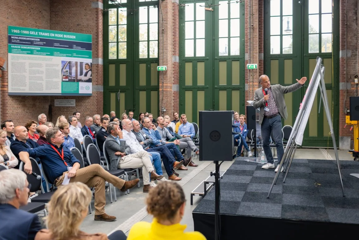 Camillo Spratt tijdens een presentatie voor een volle zaal, bij de flip-over op het podium.